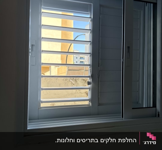 תריס הזזה לבן עם שלבים מתכווננים בחלון אלומיניום
